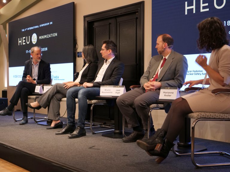 Fem personar sit ved sida av kvarandre på ei scene. Storskjermar i bakgrunnen.